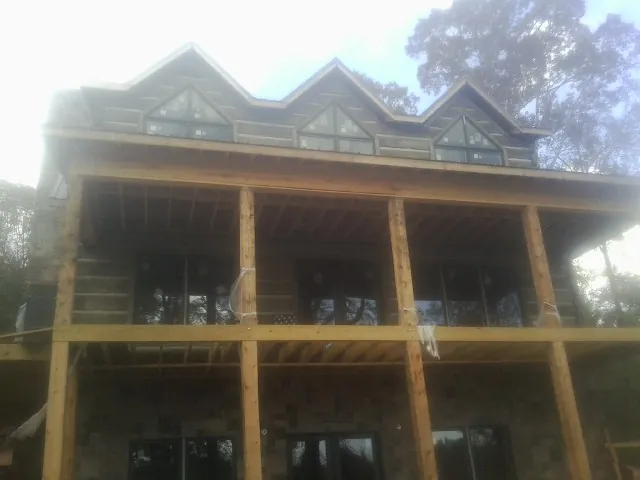 Dormers and porch framing on a large log home under construction — Roof Coating work by our crew in Seaview