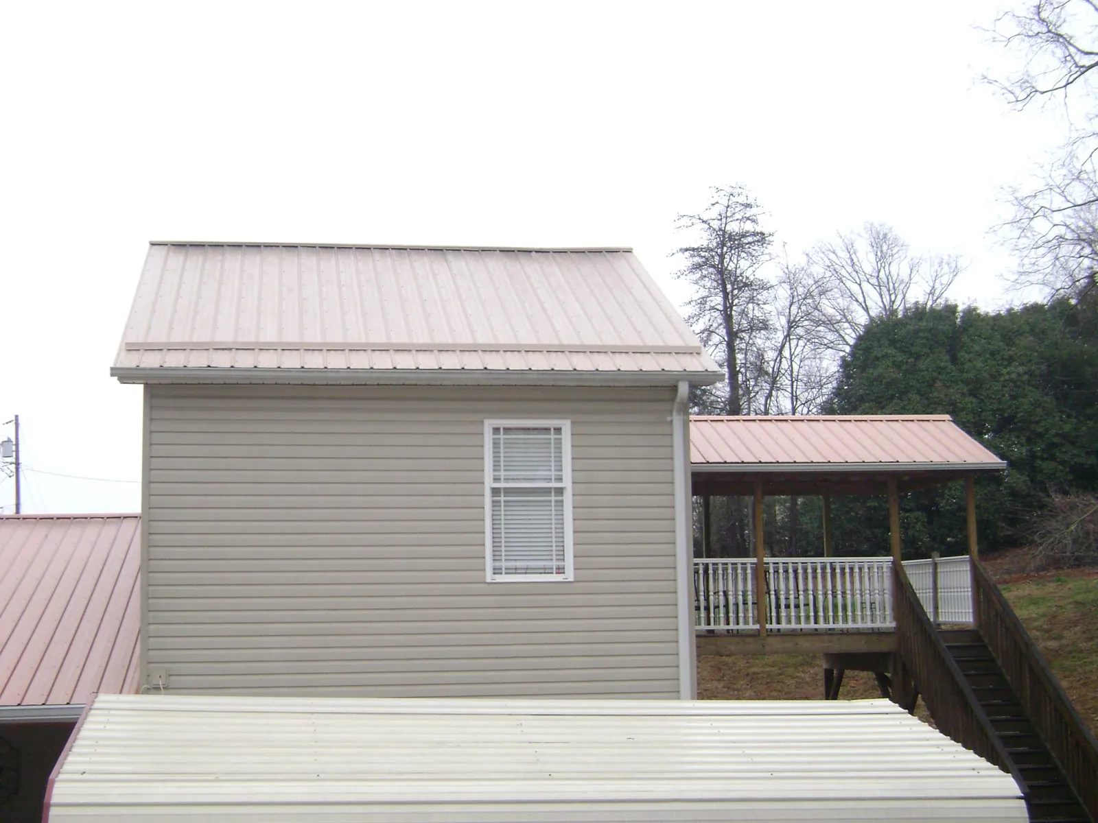 Tan metal roofs on a two story addition and attached porch, from a Roof Replacement job in Seaview