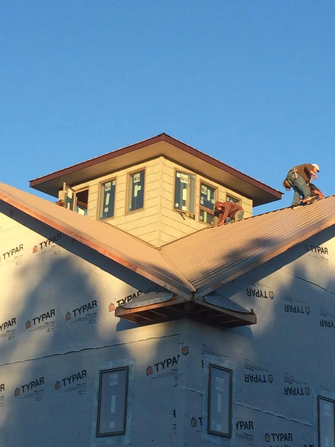 Roofers working around a rooftop cupola on a new metal roof at sunset — Roof Waterproofing in Seaview by Roofing Brothers